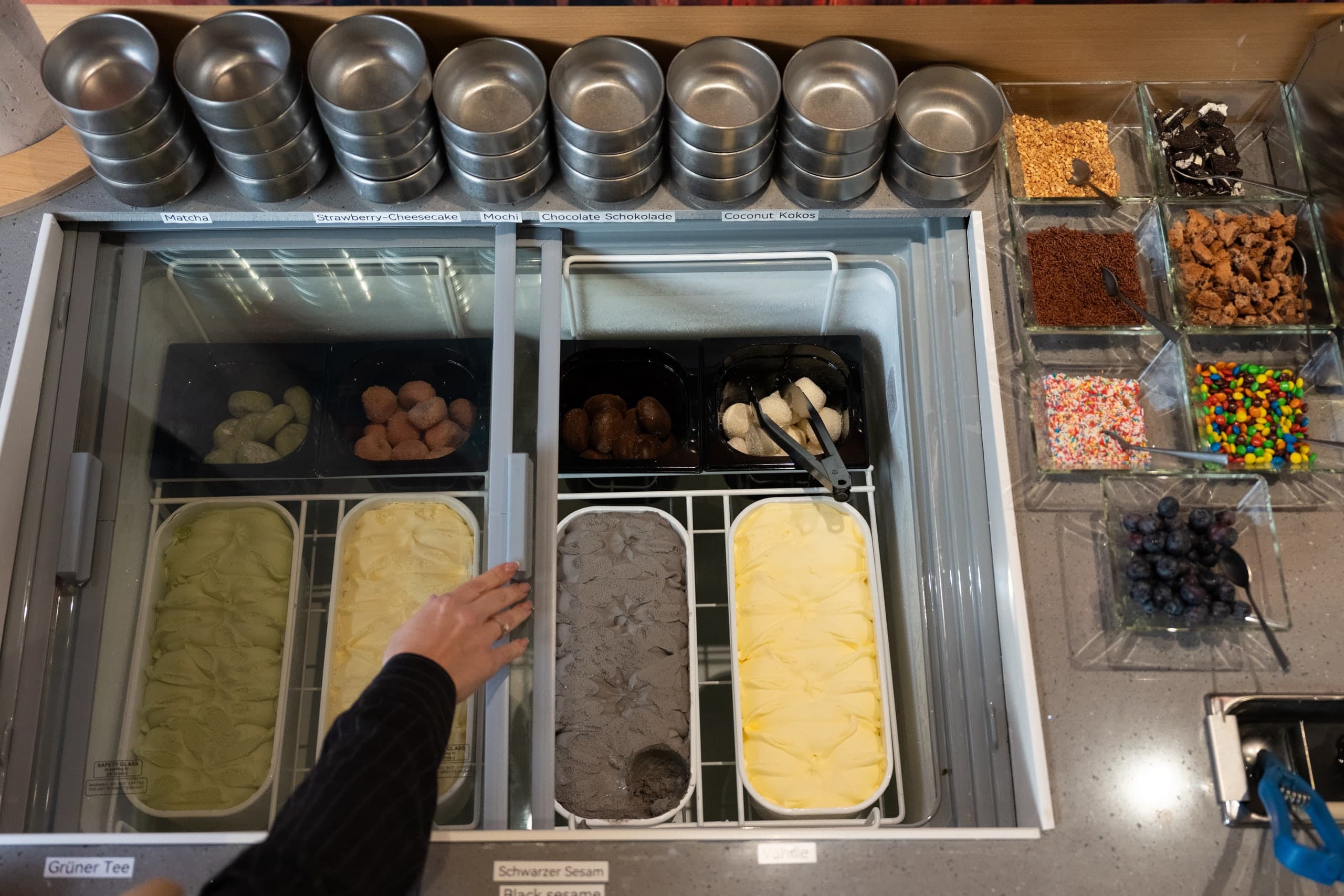 Eistheke von oben mit mehreren Eissorten und Toppings