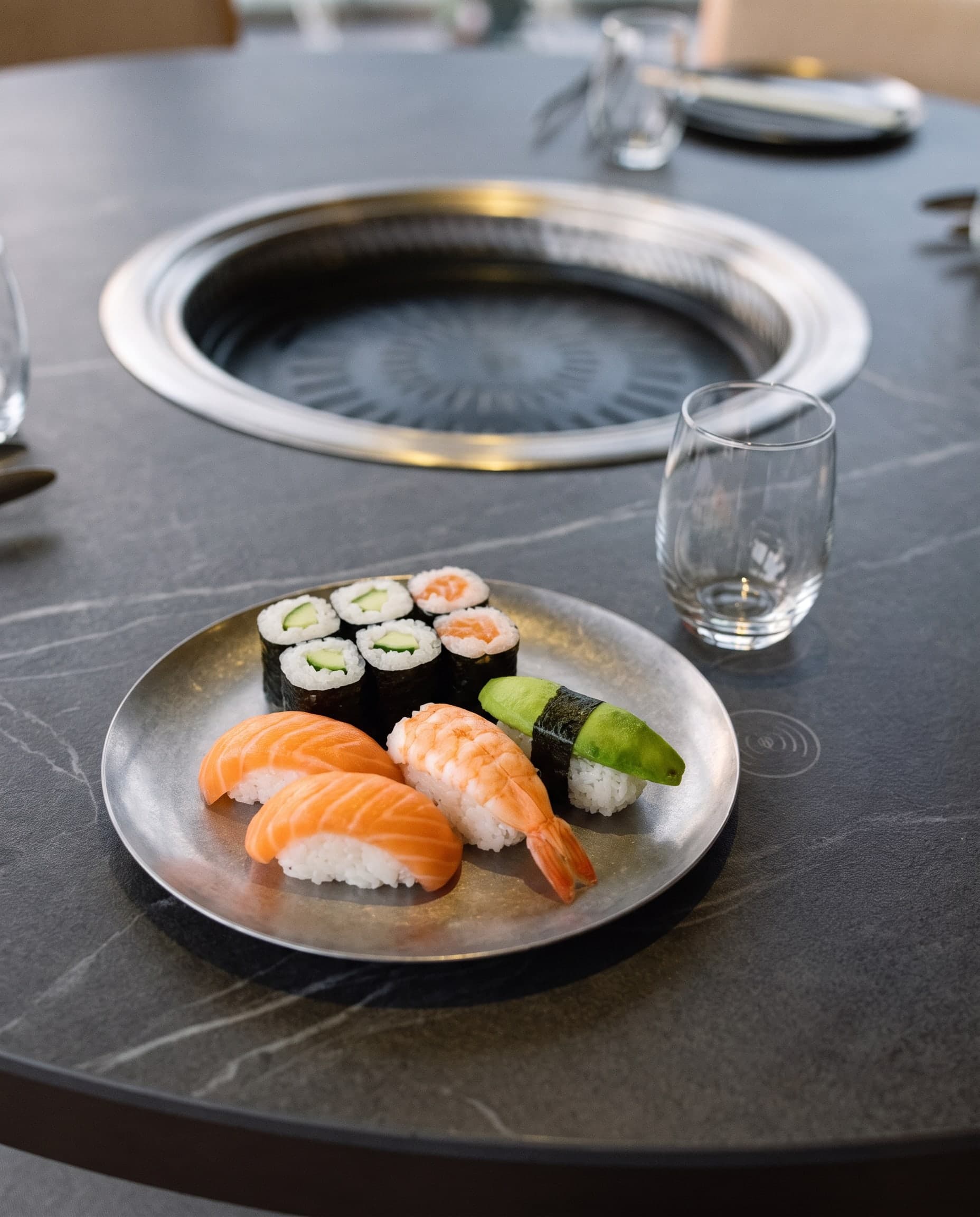 Teller mit Nigiri mit Lachs, Garnele und Avocado und Maki mit Gurke und Lachs am Tischgrill
