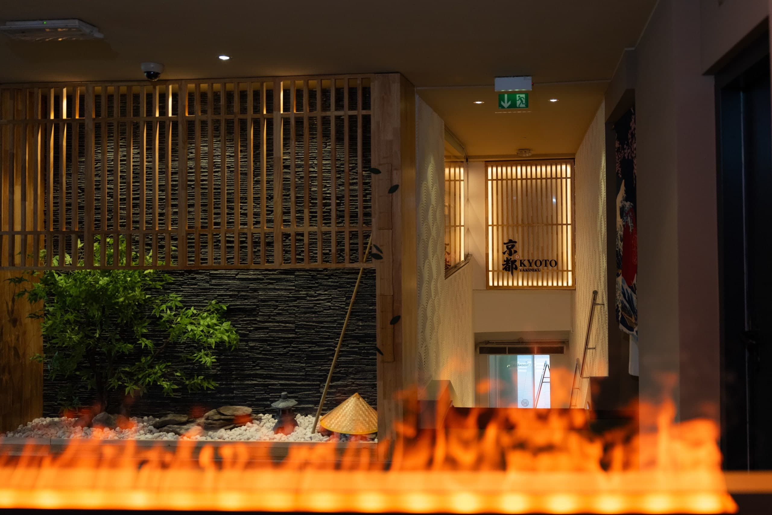 Flammen-Element vor einem kleinen Steingarten mit Pflanze und Holzgittern