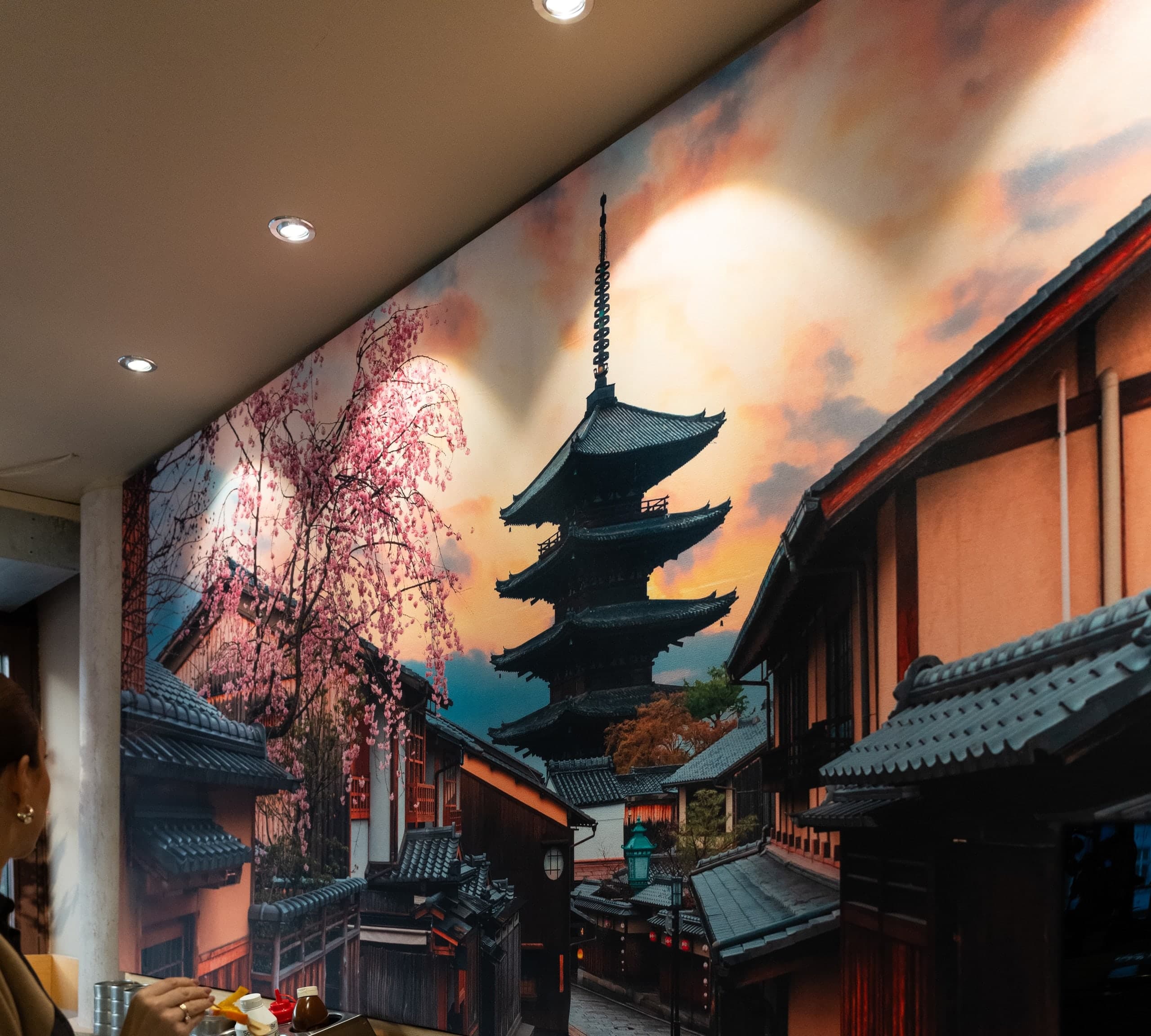 Wandbild im Restaurant: Pagode und Kirschblüten im Abendlicht, angestrahlt von Deckenstrahlern