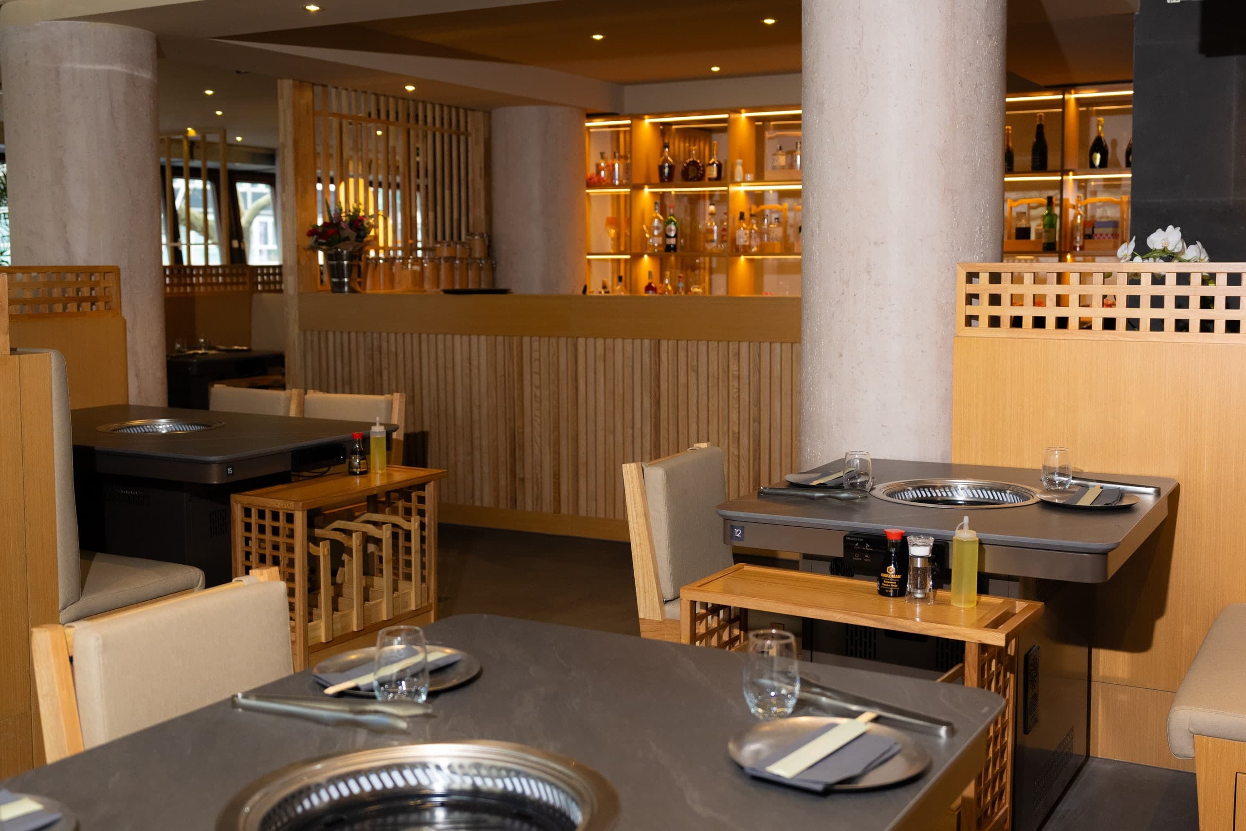 Tischgrills mit Steinplatte und Bambusholz vor der beleuchteten Bar